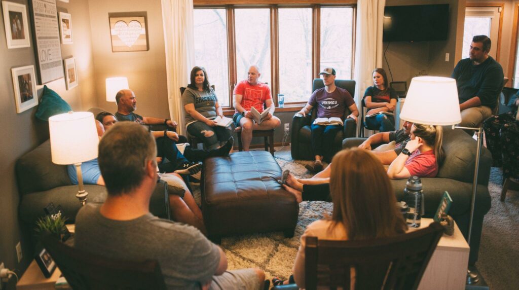 A group of 12 people gathered casually in a living room. Just about the right amount for a personalised direct marketing campaign.