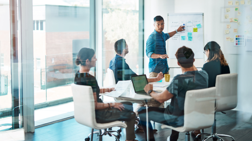 Team meeting with man by a white board explaining his ideas